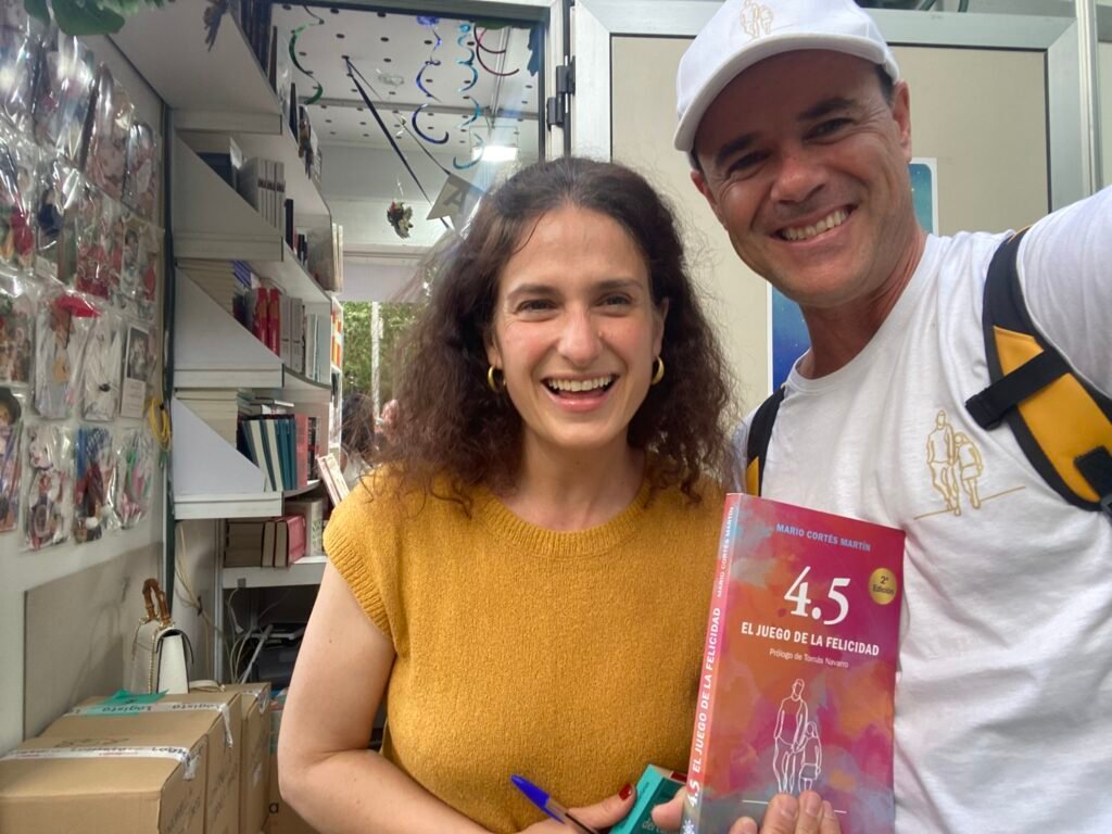 Nazareth Castellanos y Mario Cortés posando con el libro 4.5 el juego de la felicidad